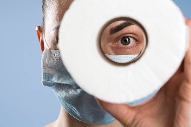 Free photo front view of woman with medical mask looking through toilet paper