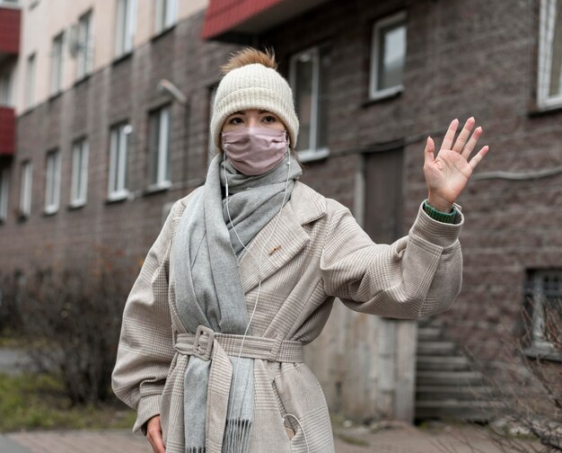 Front view of woman with medical mask waving