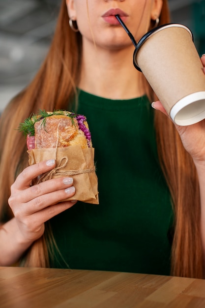 Foto gratuita vista anteriore donna con panino avvolto in carta