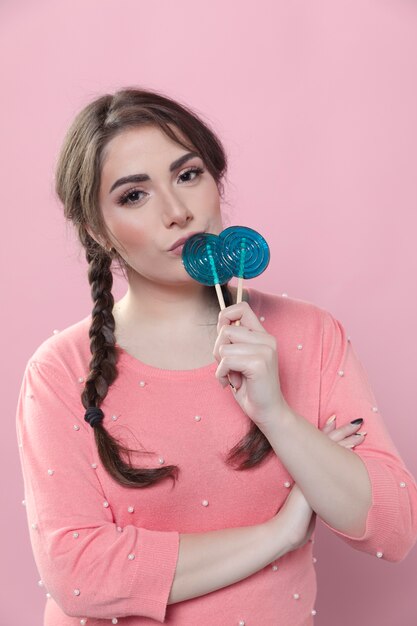 Front view of woman with ponytails posing with lollipops