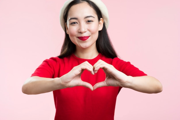 Front view woman with red lips showing heart shape with hands