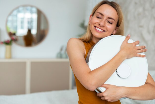 Front view woman with robotic vacuum cleaner at home