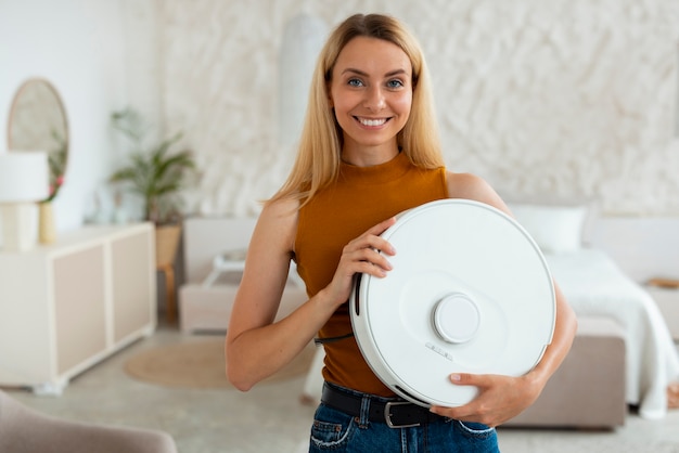 Front view woman with robotic vacuum cleaner at home