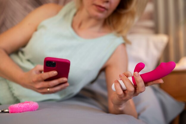 Front view woman with smartphone and vibrator