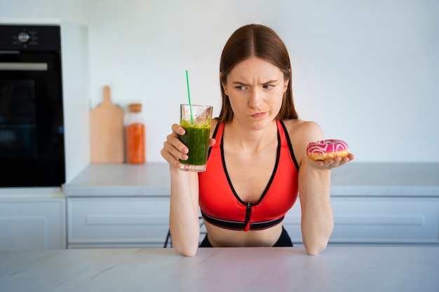 Front view woman with smoothie and doughnut