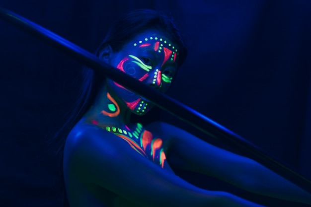 Front view of woman with stick and fluorescent make-up