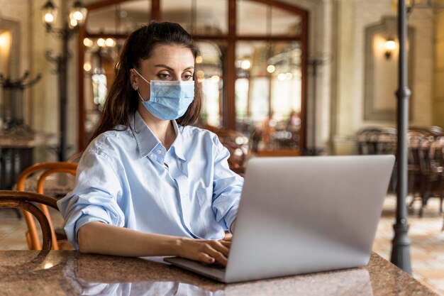 Front view woman working indoors while wearing a face mask