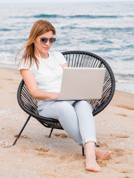 Front view of woman working on laptop in beach chair