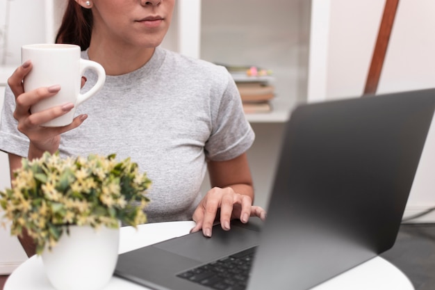 Free photo front view of woman working on laptop while holding mug