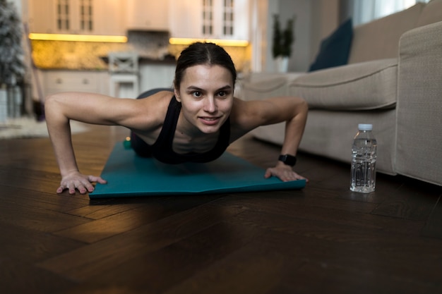 Vista frontale della donna sulla stuoia di yoga con bottiglia d'acqua