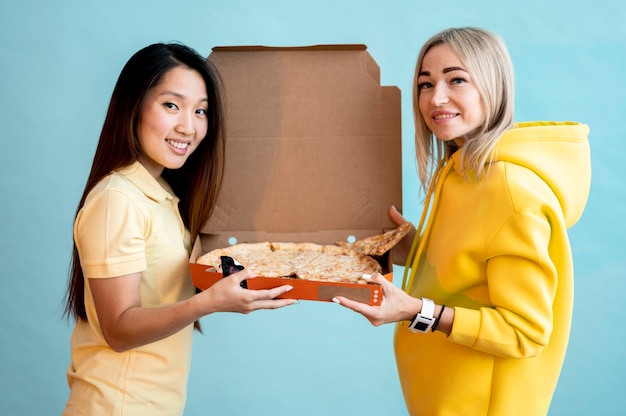 Free photo front view women holding a box with pizza