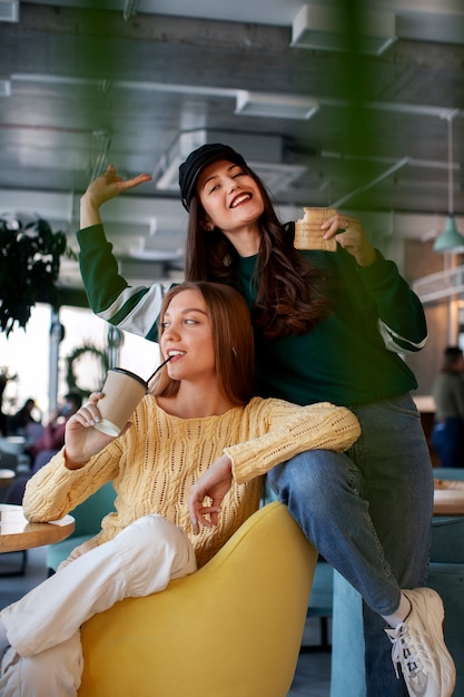 Free photo front view women holding  paper-wrapped sandwich