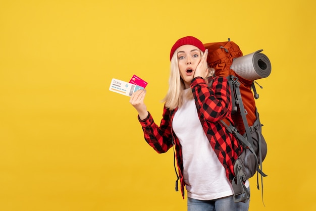 Front view wondered blonde girl with her backpack holding card and travel ticket