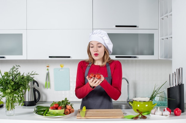 Front view wondered female cook in apron holding tomatoes