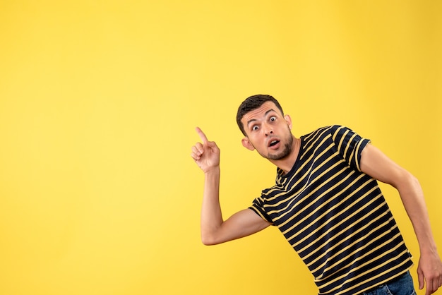 Front view wondered handsome man in black and white striped t-shirt yellow isolated background copy place