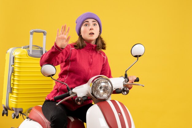 Front view wondered young girl on moped waving hand