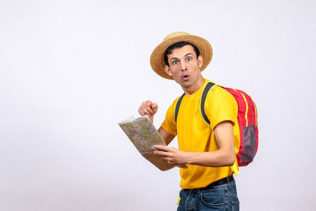 Front view wondered young man with red knapsack and yellow t-shirt pointing at map