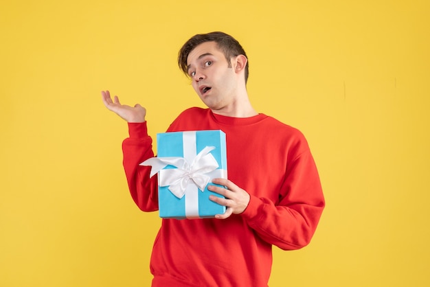 Front view wondered young man with red sweater standing on yellow 