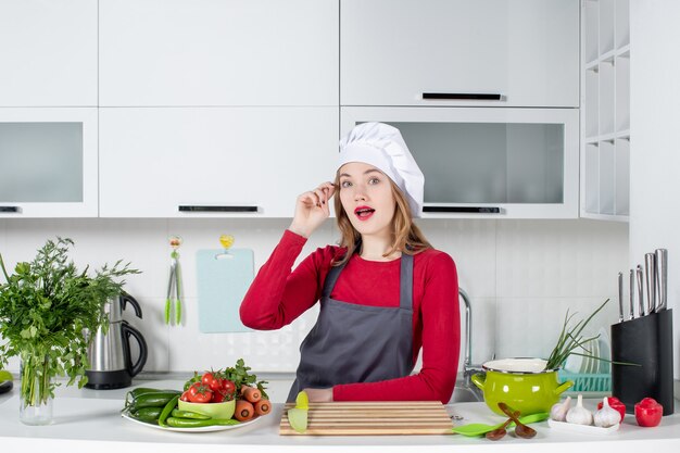 Front view wondered young woman in apron standing in kitchen