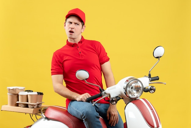 Vista frontale del giovane ragazzo che indossa la camicetta rossa e cappello che consegna gli ordini su sfondo giallo