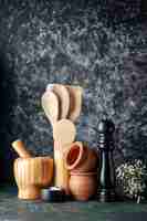 Free photo front view wooden spoons with pepper shaker on a dark wall photo color cuisine seasoning salt food cutlery