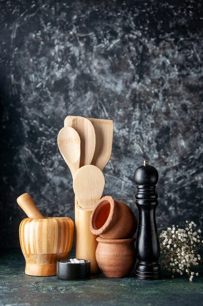 Вид спереди деревянные ложки с шейкер для перца на темной стене фото цветная кухня приправа соль пищевые столовые приборы