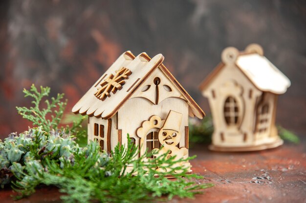 Front view wooden toy house pine tree branches on dark isolated table