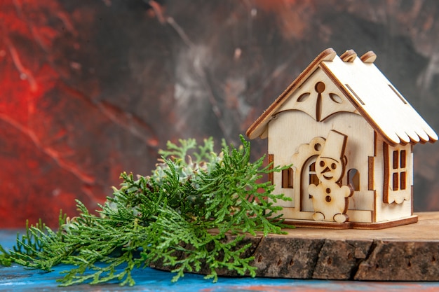 Front view wooden toy house pine tree branches on dark red table