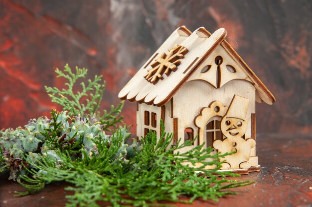 Front view wooden toy house pine tree branches on dark red table