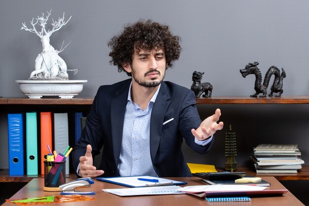 Front view of work process confused office worker in formal wear sitting at desk