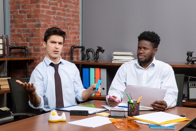現代のオフィスの机に座って話し合う2人のビジネスマンの正面図の作業プロセス