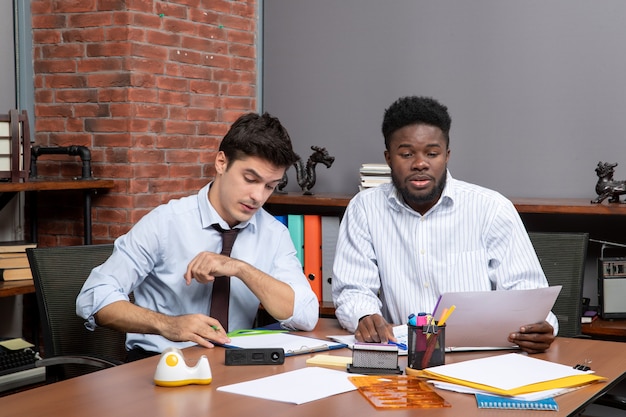 Free photo front view work process two businessmen in formal wear working in office