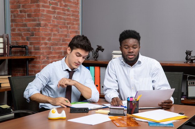 Front view work process two businessmen in formal wear working in office