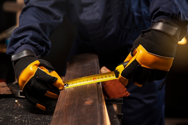 Lavoratore di vista frontale che misura pezzo di legno