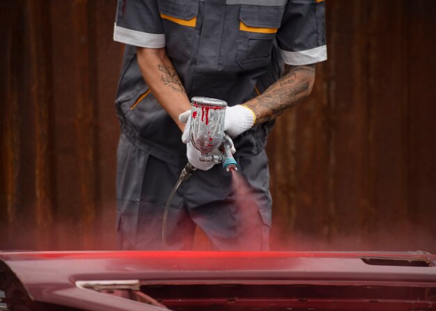Работник, вид спереди, распыляет порошковую краску из жевательной резинки