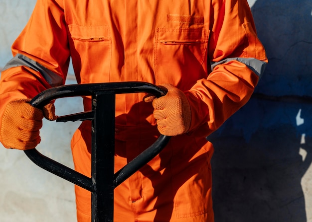 Lavoratore di vista frontale in uniforme con guanti protettivi che maneggiano carrello elevatore