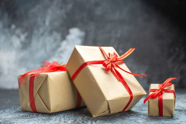 Front view xmas presents tied with red bows on light-dark color photo new year holiday christmas gift