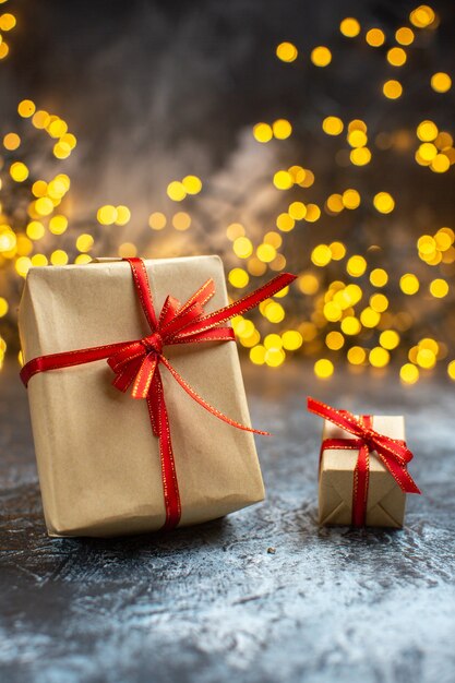 Вид спереди рождественские подарки с желтыми огнями на светло-темном фото рождество новогодний цвет