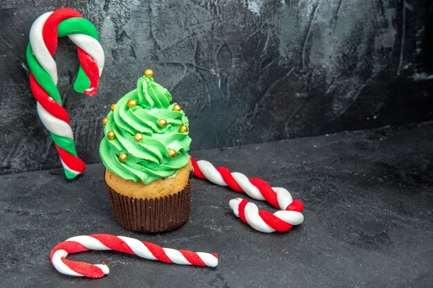 Front view xmas tree cupcake and xmas candies on dark background free place