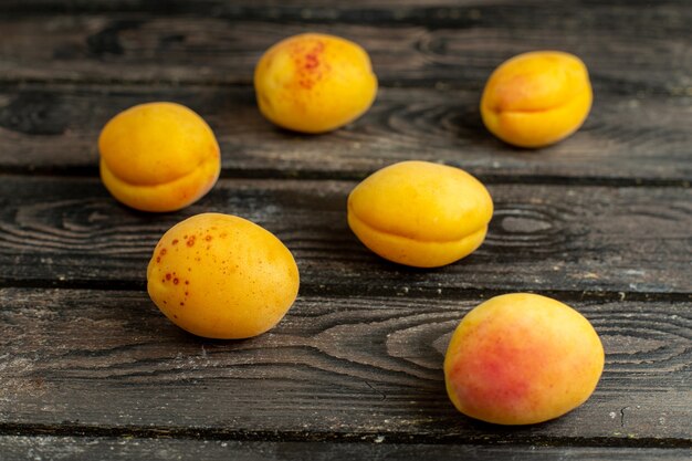 Front view yellow apricots mellow and fresh frutis on the brown rustic background 