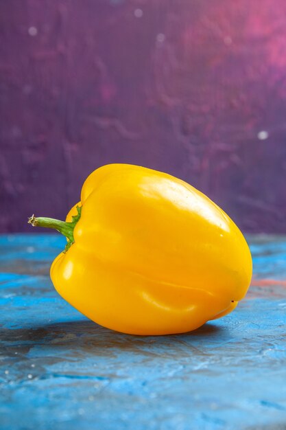 Front view yellow bell-pepper on a blue-pink table