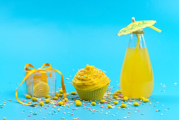A front view yellow cake with candies and fresh lemon juice on blue desk, cake biscuit sweet color