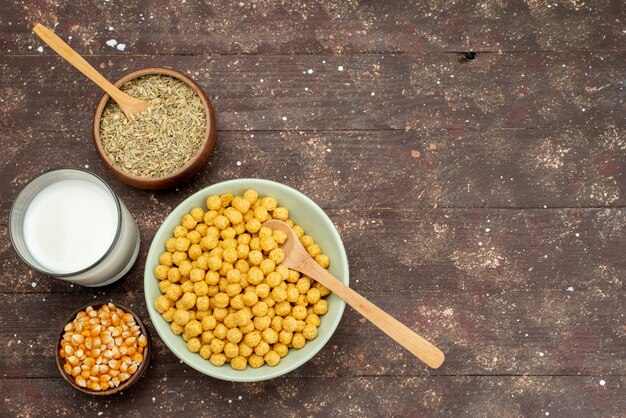 Front view yellow cereals inside plate with fresh cold milk on dark breakfast cornflakes cereals meal