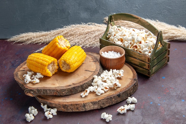 Front view yellow corns sliced with popcorn on dark surface corn snack plants tree oil