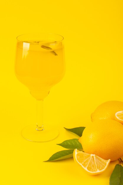 A front view yellow fresh lemons fresh ripe whole and sliced along with green leaves lemon drink fruits isolated on the yellow background citrus fruit color