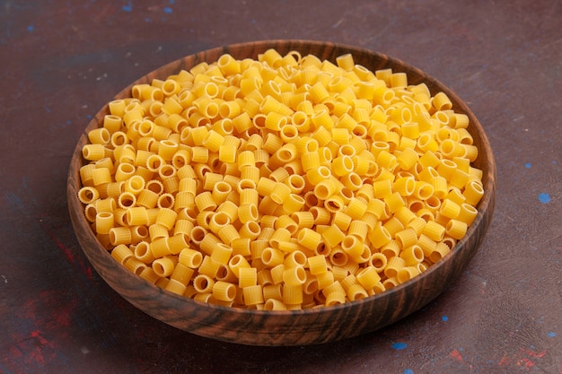 Free photo front view yellow italian pasta raw little formed on dark desk