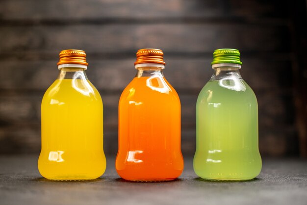 Front view yellow orange and green juice in bottles