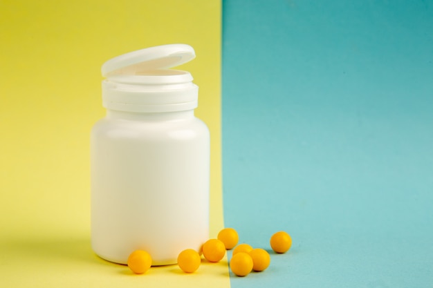 front view yellow pills with plastic flask on green-blue background