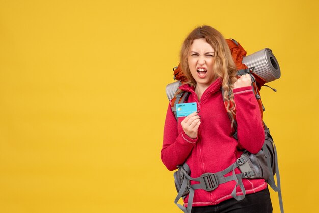 Вид спереди молодой амбициозной путешествующей девушки в медицинской маске, держащей банковскую карту