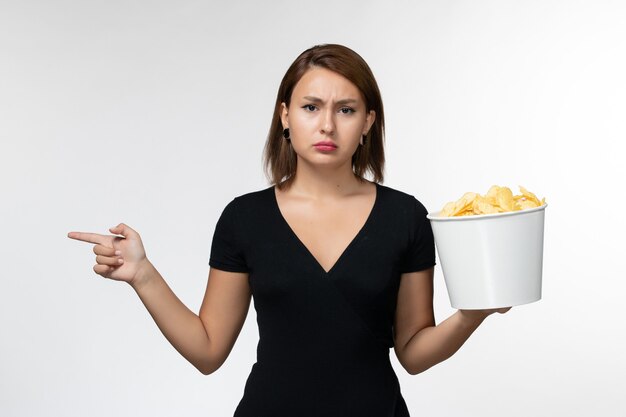 Front view young attractive female in black shirt holding potato cips on white surface